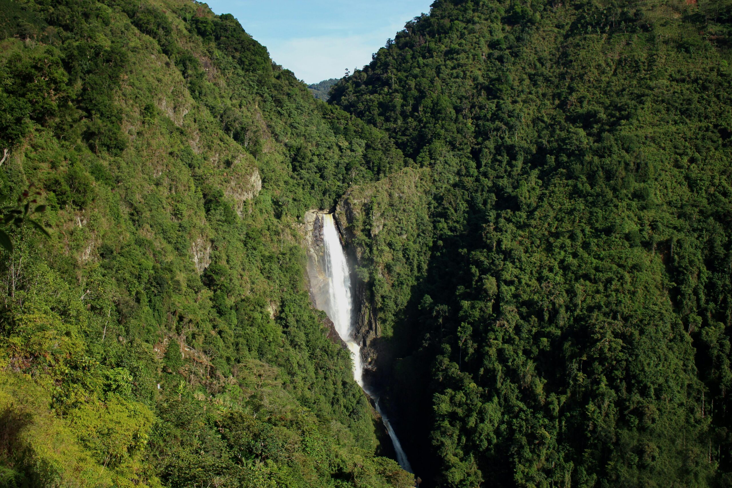 A breathtaking waterfall cascades through lush green mountains, captured in Colombia's scenic landscapes.